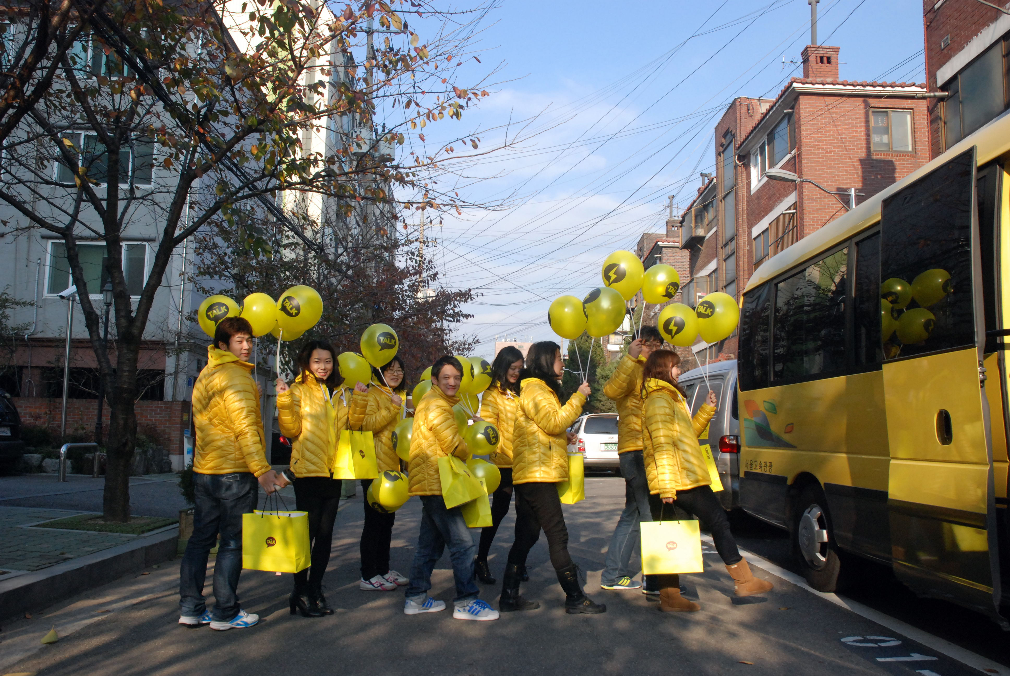 Employees who participated in the street campaign are lined up riding yellow balloons.
