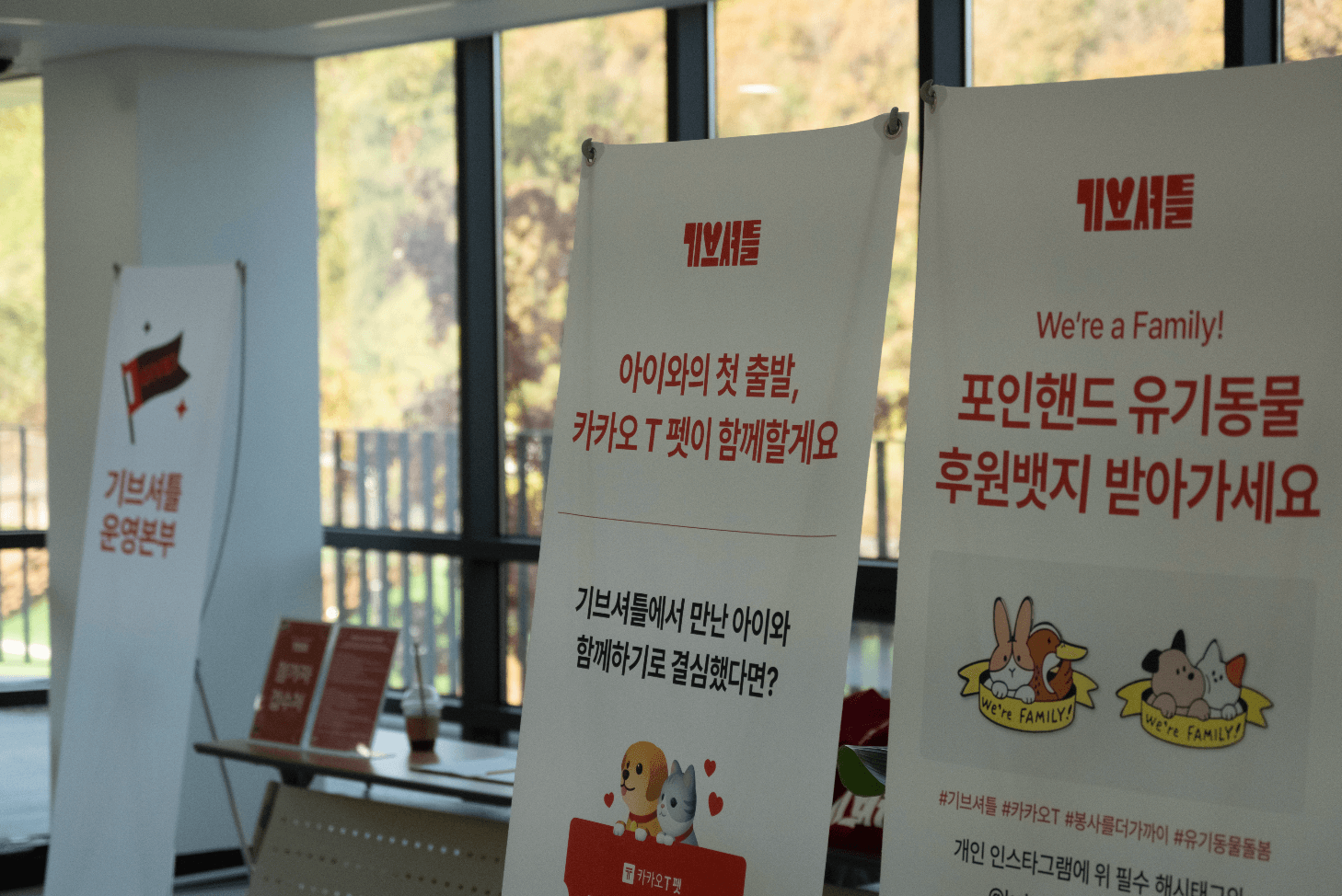 후원뱃지 안내, 기브셔틀 운영본부, 카카오 T 펫택시 등 기브셔틀 프로그램과 관련된 배너들이 현장에 배치되어 있는 모습입니다.